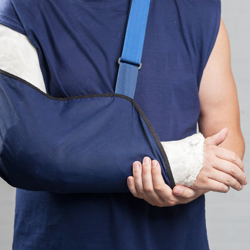 A man with a broken arm is wearing a blue bandage carrier made by Faddico.