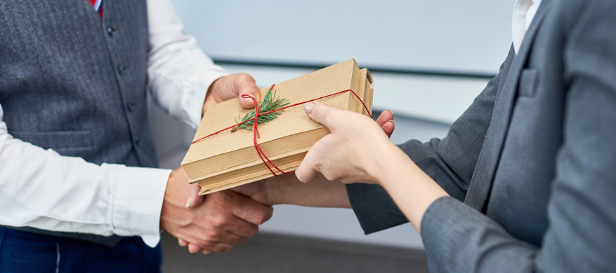 An employee receiving sustainable promotional products in a gift pack from her senior company officer.