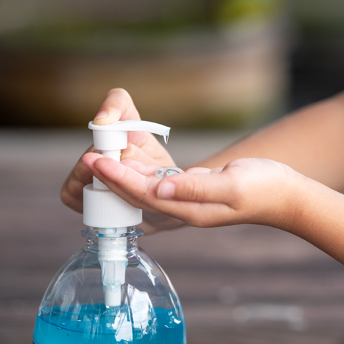 A woman is using Faddico's hand sanitizer to sanitize her hands. Faddico offers customizable health and wellness products for clients.