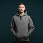 A boy in a grey hoodie stands with his hands in his pockets.