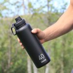 A drinkware promotional product in a man hand. A black color insulated water bottle in his hand with printed logo of a company. A drinkware promotional product
