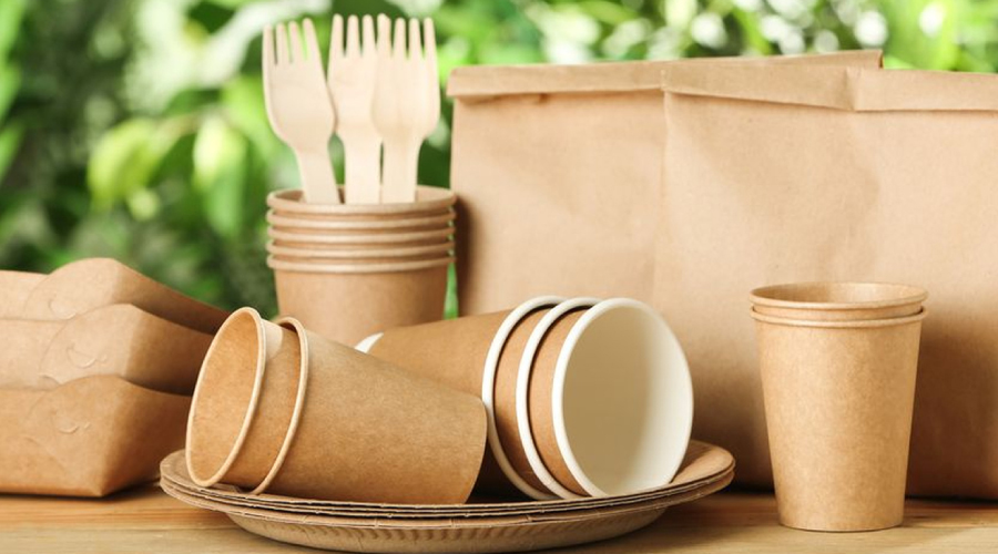 A different eco friendly promotional products like cups, spoons, plates and bags are lying on a table.