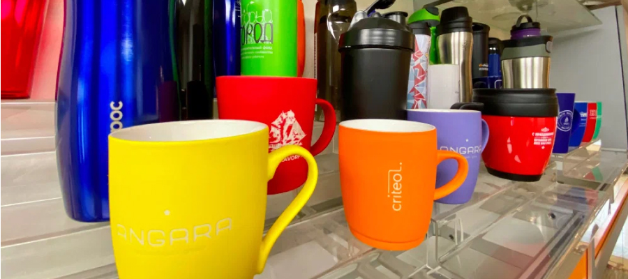 Red and yellow coffee mugs, along with insulated customized bottles, are carefully arranged.
