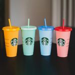 A tumblers in different color laying on a table with a company logo customized by Faddico. A great drinkware promotional product for brand awareness.