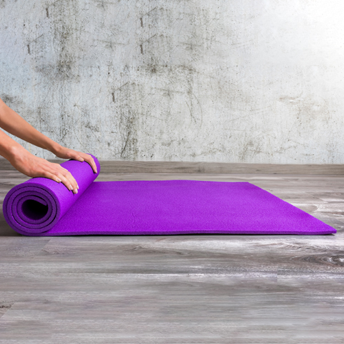 A woman is folding purple color yoga mat made by Faddico.