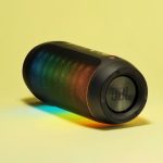 A black Bluetooth speaker is emitting lights of different colors.