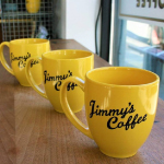 Yellow color customized branded mugs are arranged neatly in a line