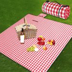A pink picnic blanket laid on green grass with a bag placed nearby