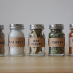 Different types of spices are kept in small glass jars.