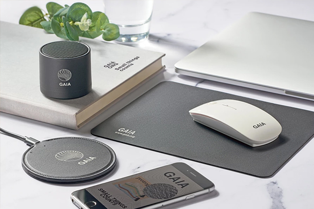 The technology promotional product including mouse, pad, Bluetooth speaker, and laptop are placed on table.