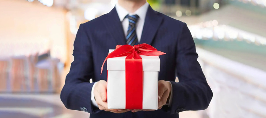An employee handing over a white gift box with both hands.