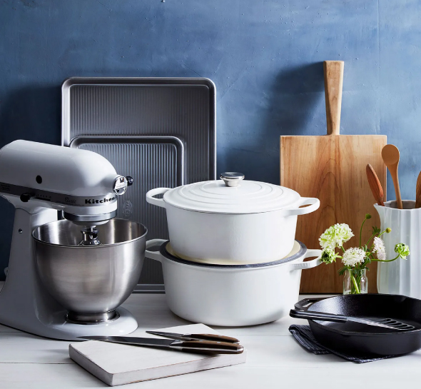 A promotional kitchen product set, including a frying pan, pots, cutting board, and knives, is placed together.
