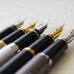 Different-colored pens are placed with their caps off.
