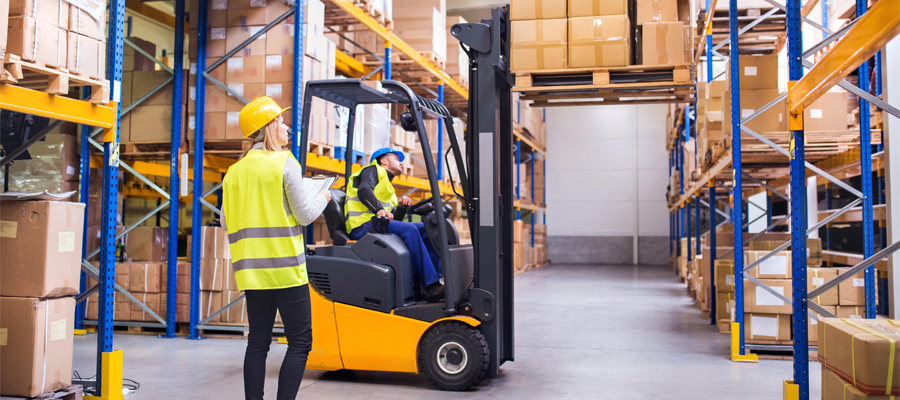 Workers in safety vests with a forklift in a warehouse - Benefits of Warehousing