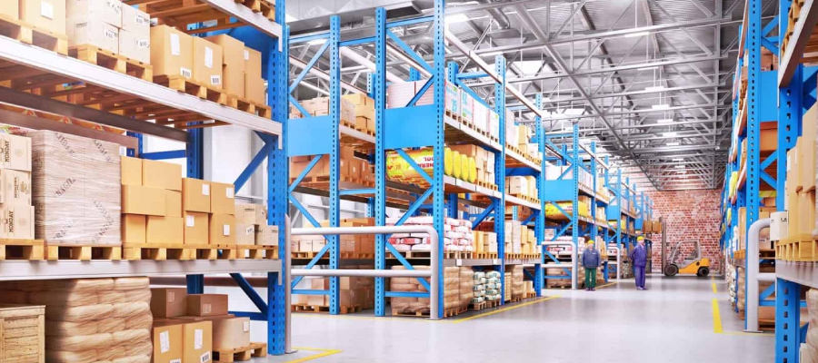 A spacious warehouse with tall blue shelving stocked with various boxes and workers in the aisle-Choosing The Right Warehouse