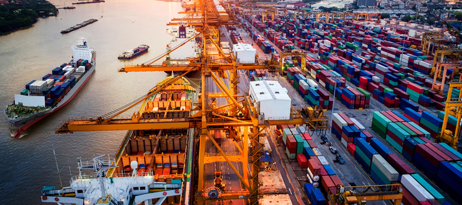 A sunset view at a port where international import and export operations take place, with cargo ships and containers in the background.